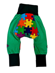 Green pants with colorful puzzle piece pattern on a white background